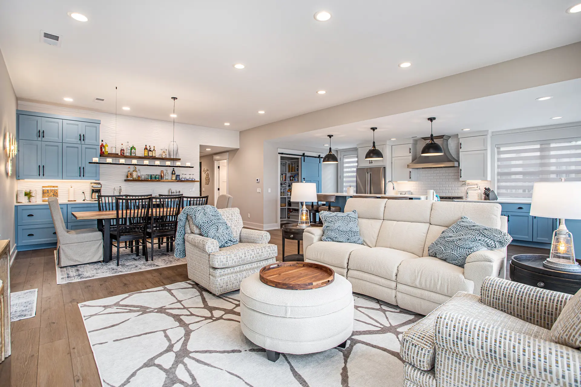 Open concept living room, dining area, kitchen, and blue beverage bar in a lakefront home