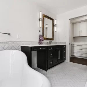 Laundry room with white custom cabinetry, marble-look counters, dark washer and dryer, and wood flooring in a downtown Kalamazoo condominium