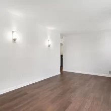 Unfurnished flex room with dark wood flooring, neutral walls, white trim, and modern wall sconces in a downtown Kalamazoo condominium