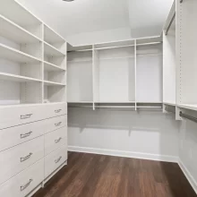 Walk-in closet with dark wood flooring and a custom white closet system in a downtown Kalamazoo condominium
