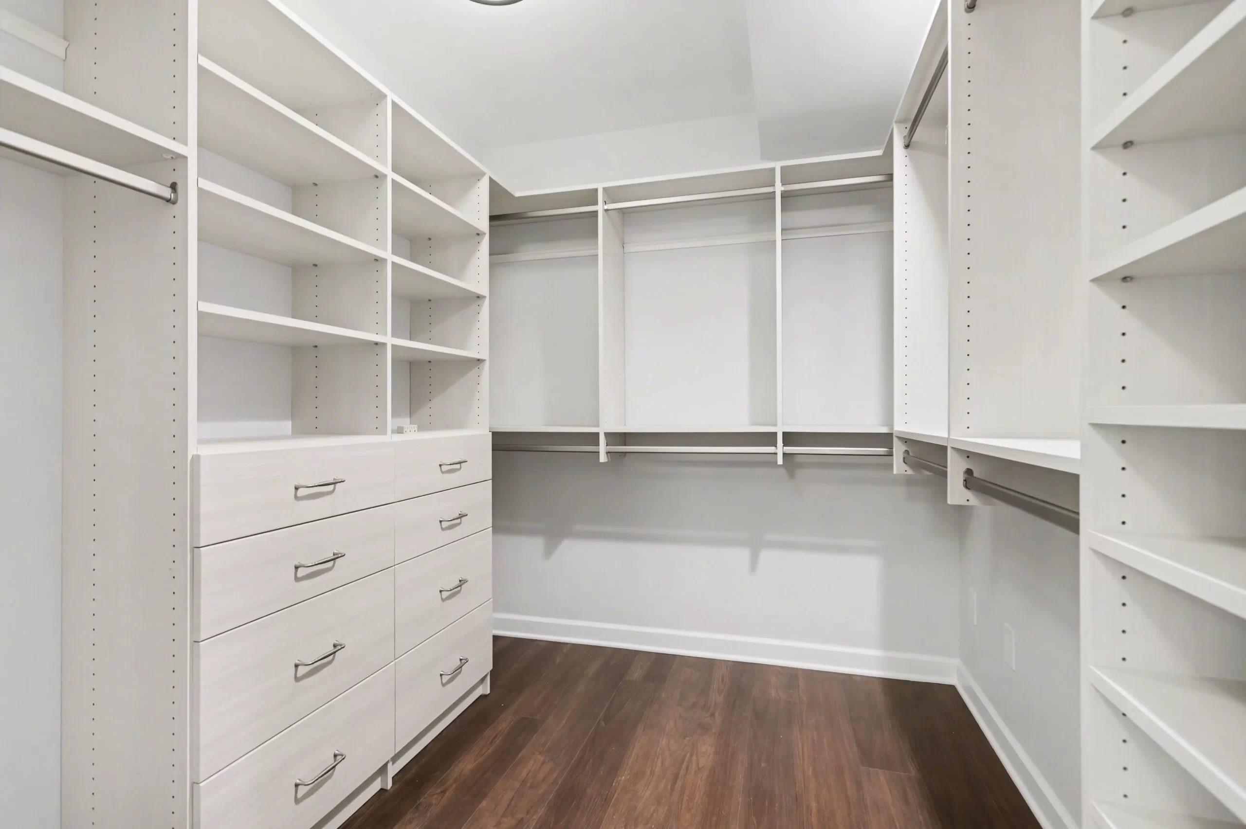 Walk-in closet with dark wood flooring and a custom white closet system in a downtown Kalamazoo condominium