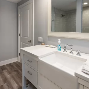 Bathroom vanity with farmhouse-style sink, chrome fixtures, framed mirror, gray walls, and wood-look flooring