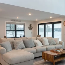 Living room with sectional sofa, built-in wet bar, black-framed windows, and lake views