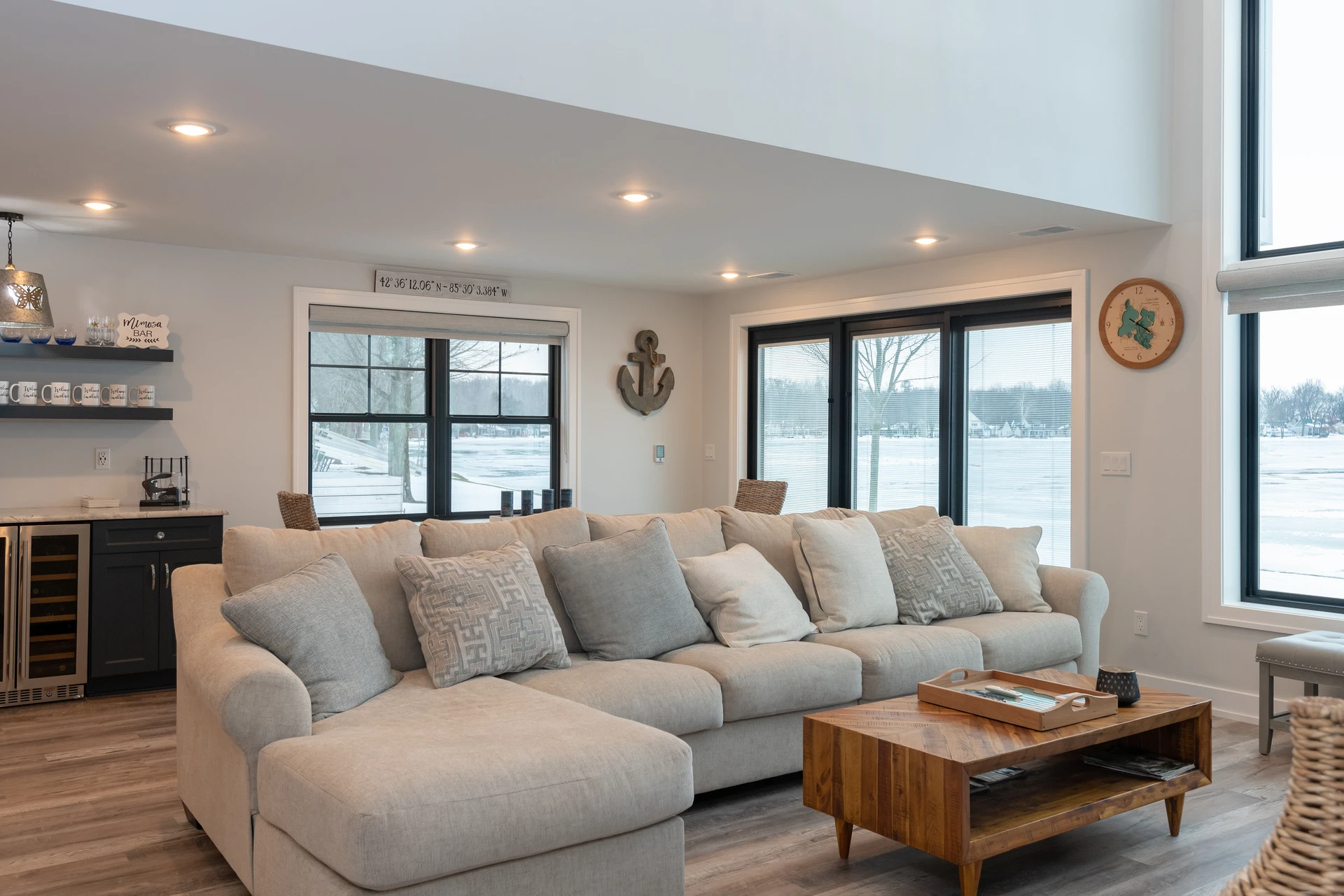 Living room with sectional sofa, built-in wet bar, black-framed windows, and lake views