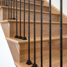 Close-up of custom wood stair treads with rounded nosing and black metal balusters