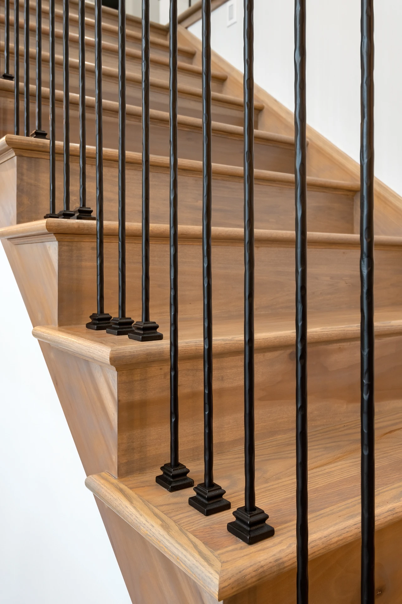Close-up of custom wood stair treads with rounded nosing and black metal balusters
