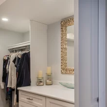 Walk-in closet with white vanity drawers, countertop, decorative mirror, hanging storage, and pocket door