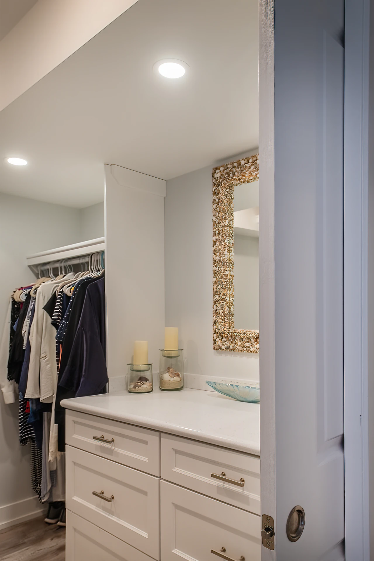 Walk-in closet with white vanity drawers, countertop, decorative mirror, hanging storage, and pocket door