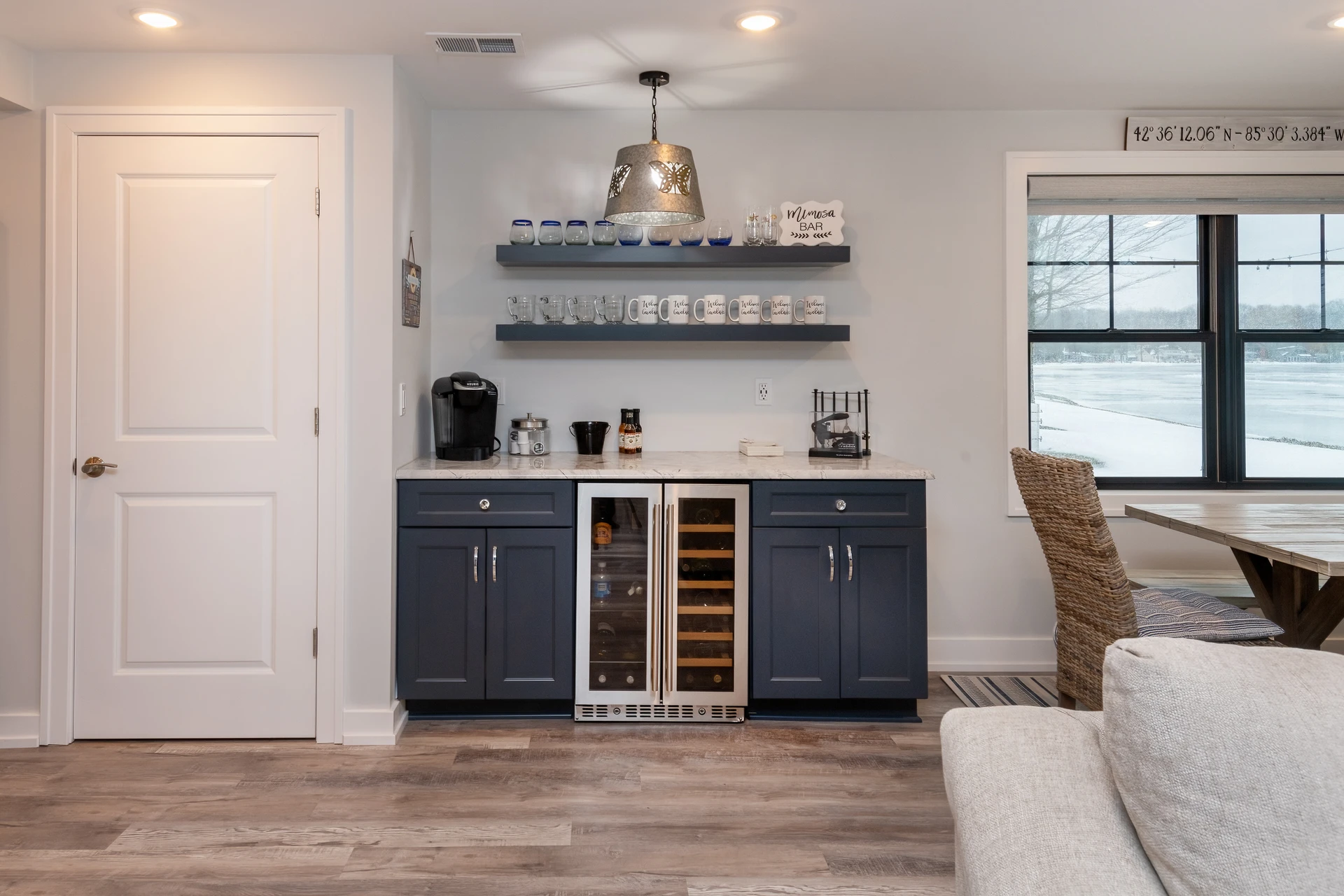 Built-in wet bar with dark cabinetry, floating shelves, wine fridge, beverage station, and lake view window