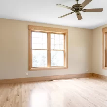 Bedroom with light wood flooring, natural wood window trim, matching baseboards, and neutral walls