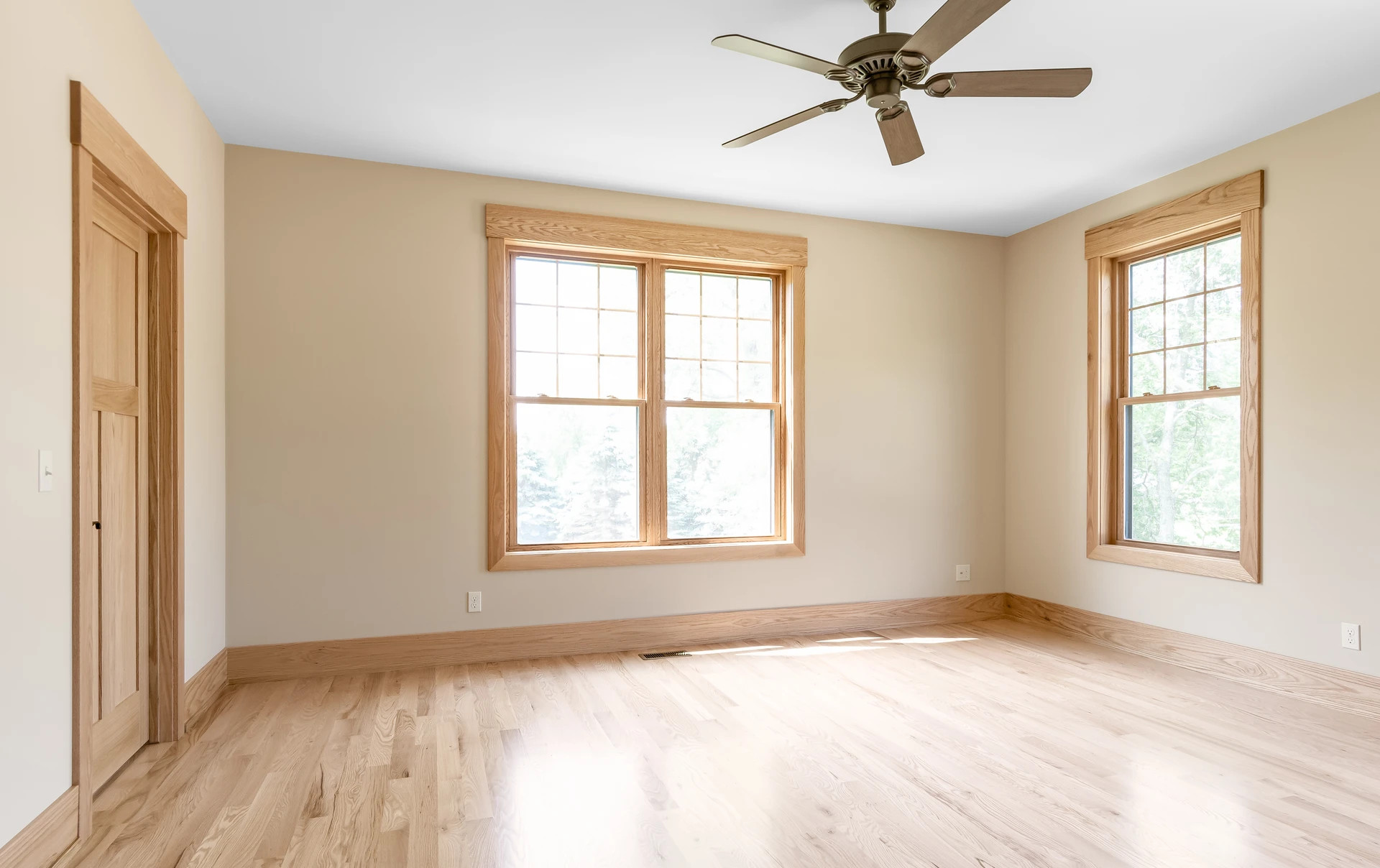 Bedroom with light wood flooring, natural wood window trim, matching baseboards, and neutral walls