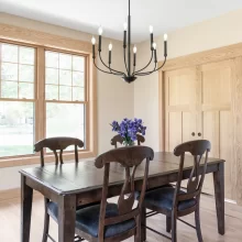 Dining room with natural wood window trim, matching closet doors, light wood flooring, and black chandelier