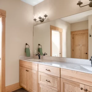 Bathroom with natural wood double vanity, large wall mirror, black fixtures, and matching wood door trim