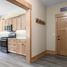Kitchen entry view with natural wood cabinetry, matching door trim, wood door, and gray-toned flooring