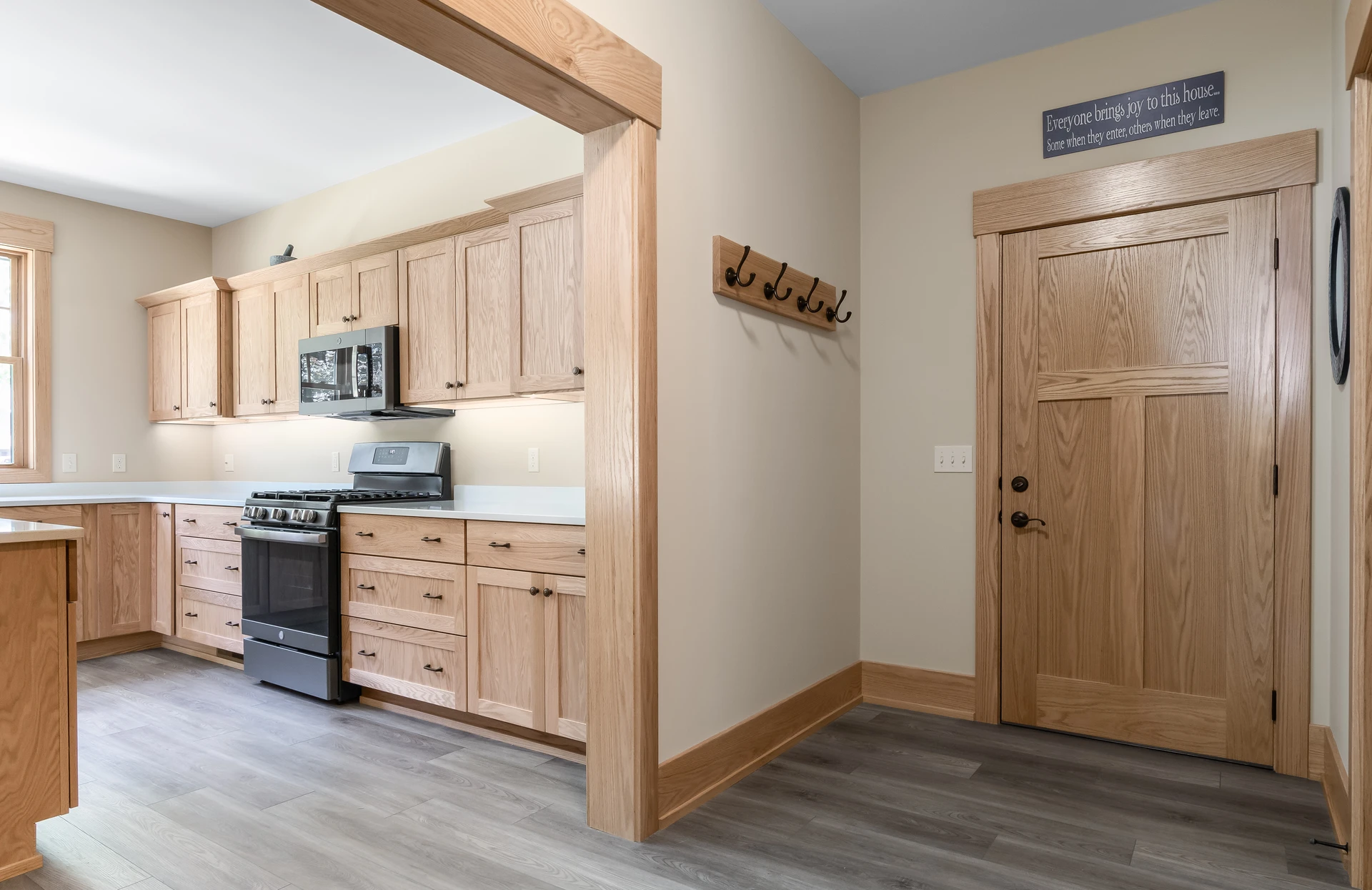 Kitchen entry view with natural wood cabinetry, matching door trim, wood door, and gray-toned flooring