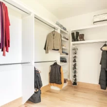 Walk-in closet with open shelving, hanging rods, light wood flooring, and organized clothing storage