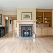 Wide living room view showing a custom wood fireplace surround, built-in bookcases, wood trim, and light flooring