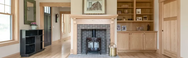 Wide Living Room View with Fireplace Built-Ins | Pennings & Sons Wide living room view showing a custom wood fireplace surround, built-in bookcases, wood trim, and light flooring