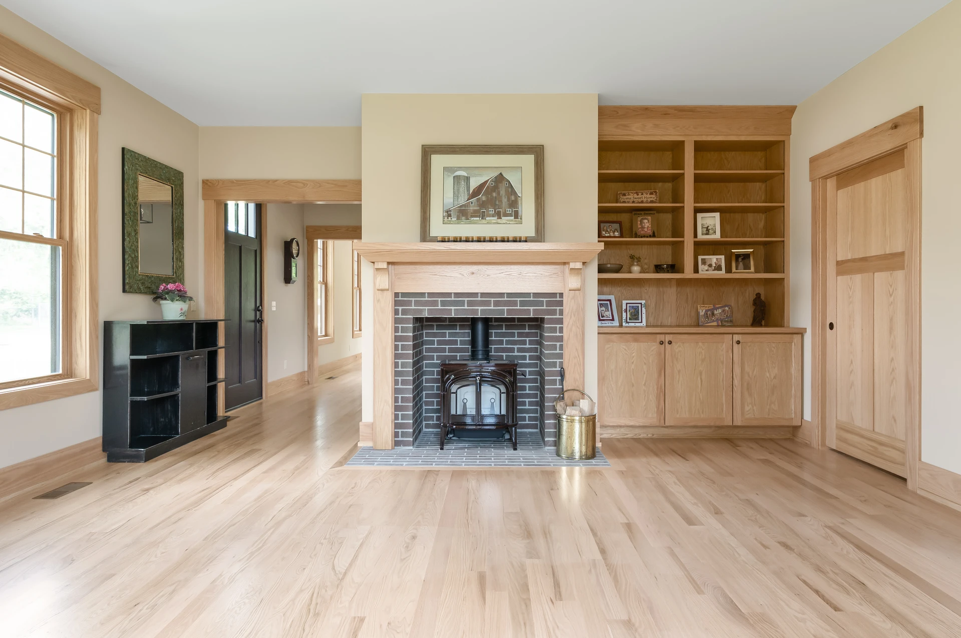 Wide living room view showing a custom wood fireplace surround, built-in bookcases, wood trim, and light flooring