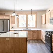 Remodeled kitchen with natural wood cabinets, island seating, window over the sink, and stainless appliances