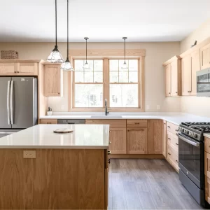 Remodeled kitchen with natural wood cabinets, island seating, window over the sink, and stainless appliances