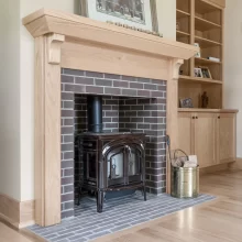 Custom wood mantel surrounding a brick stove fireplace with built-in cabinetry and shelving nearby