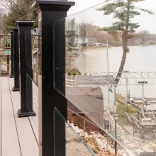 Lakefront deck with glass railing, black posts, composite decking, and shoreline views across the water