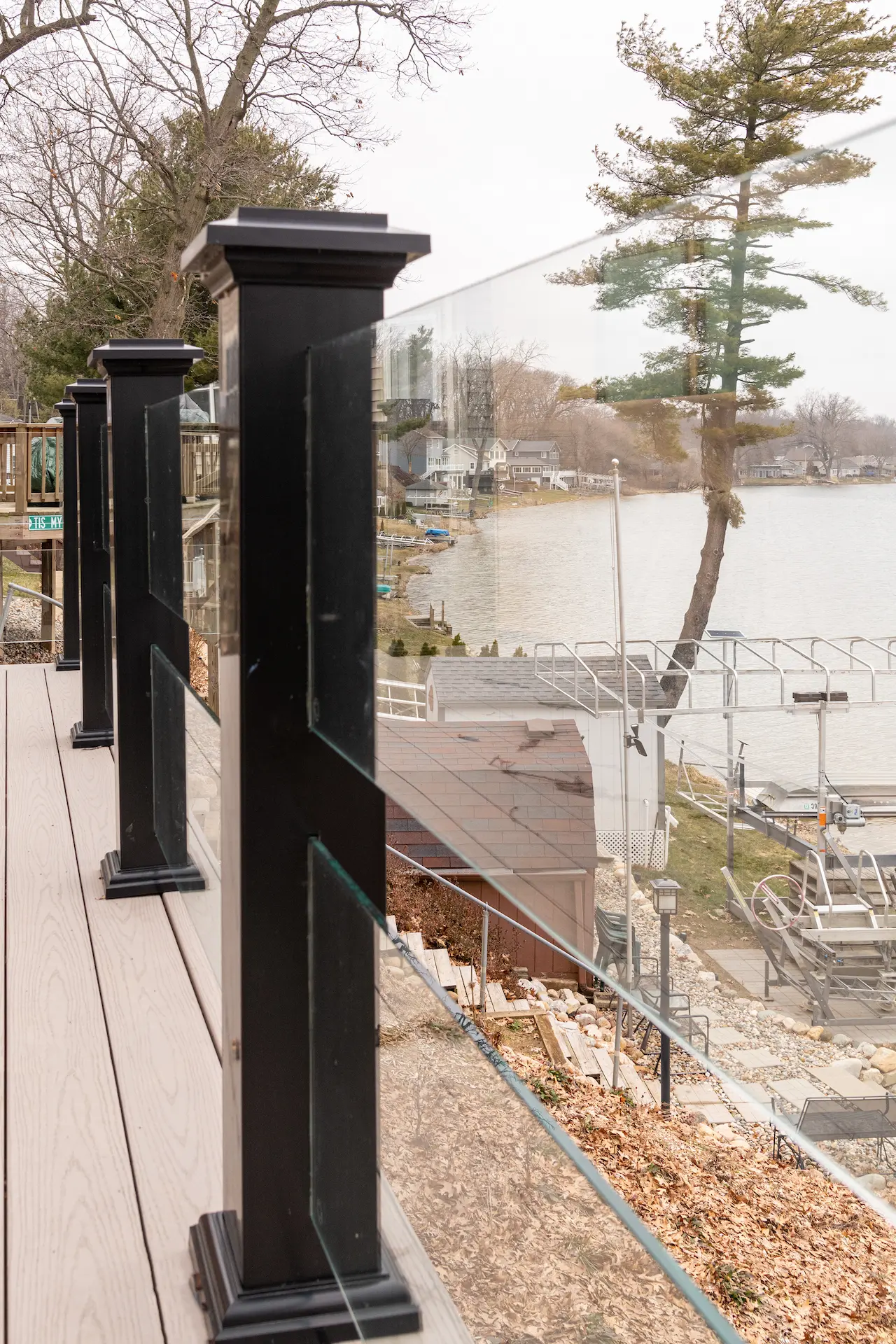 Lakefront deck with glass railing, black posts, composite decking, and shoreline views across the water