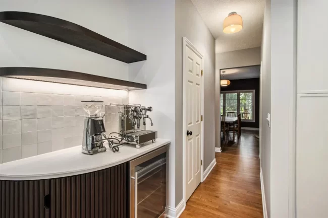 Custom Coffee Bar with Fluted Cabinet and Wine Fridge | Pennings & Sons Custom coffee bar with fluted dark wood cabinet, floating shelves, tile backsplash, espresso machine, and beverage fridge