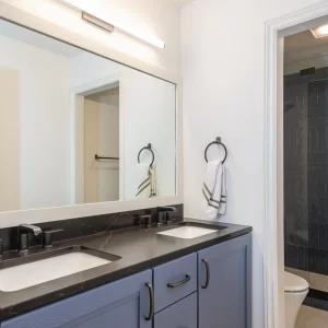 Blue bathroom vanity with black countertop and a walk-in tiled shower beyond the doorway