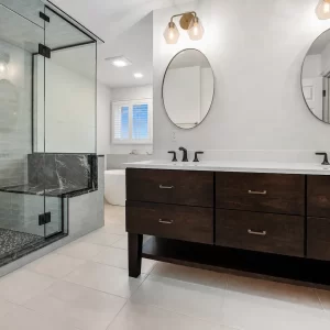 Spacious bathroom with glass shower enclosure, pale green storage cabinet, tile flooring, window, and soft blue-green trim