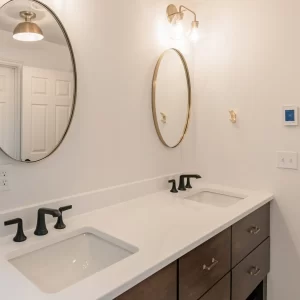 Modern primary bathroom with a dark wood double vanity, glass shower, and freestanding tub