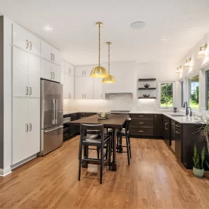 Remodeled kitchen with white upper cabinets, dark lower cabinets, wood floors, table & seating, and built-in coffee bar