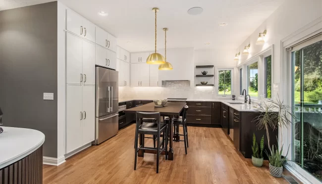 Remodeled Kitchen with Coffee Bar and Open Layout | Pennings & Sons Remodeled kitchen with white upper cabinets, dark lower cabinets, wood floors, table & seating, and built-in coffee bar