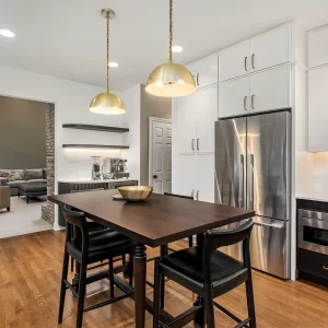 Two-tone kitchen with white cabinets, dark lower cabinetry, table seating, stainless appliances, and custom coffee bar
