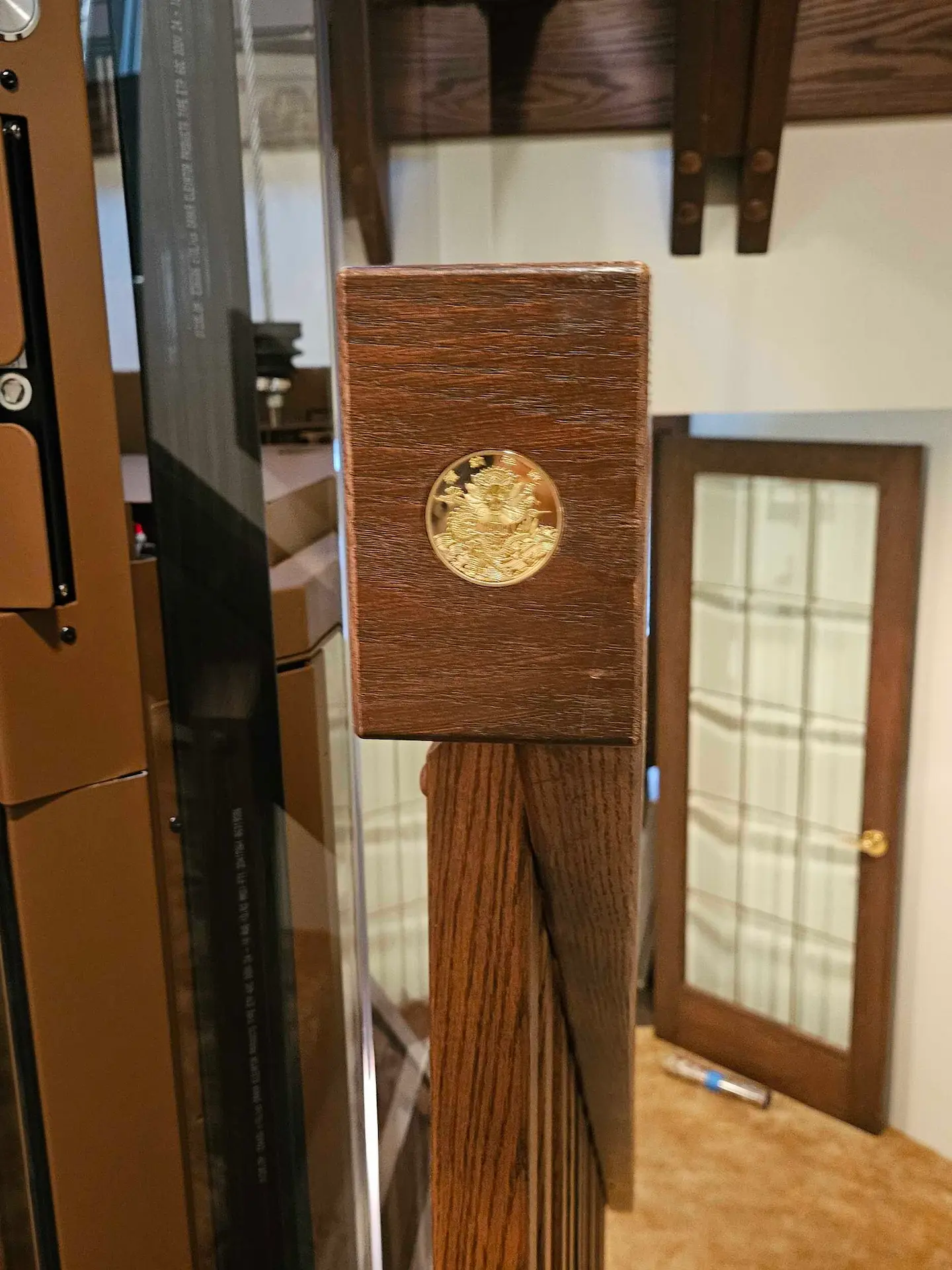 Wood Housing for Elevator Call Station Button leading toward a custom home elevator with glass panels and warm brown interior finishes