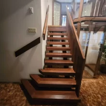 Custom wood stair treads installed beside a residential elevator with glass enclosure and warm interior finishes