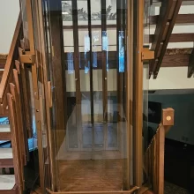 Detail photo of wood railing post and glass elevator structure in a custom residential elevator installation