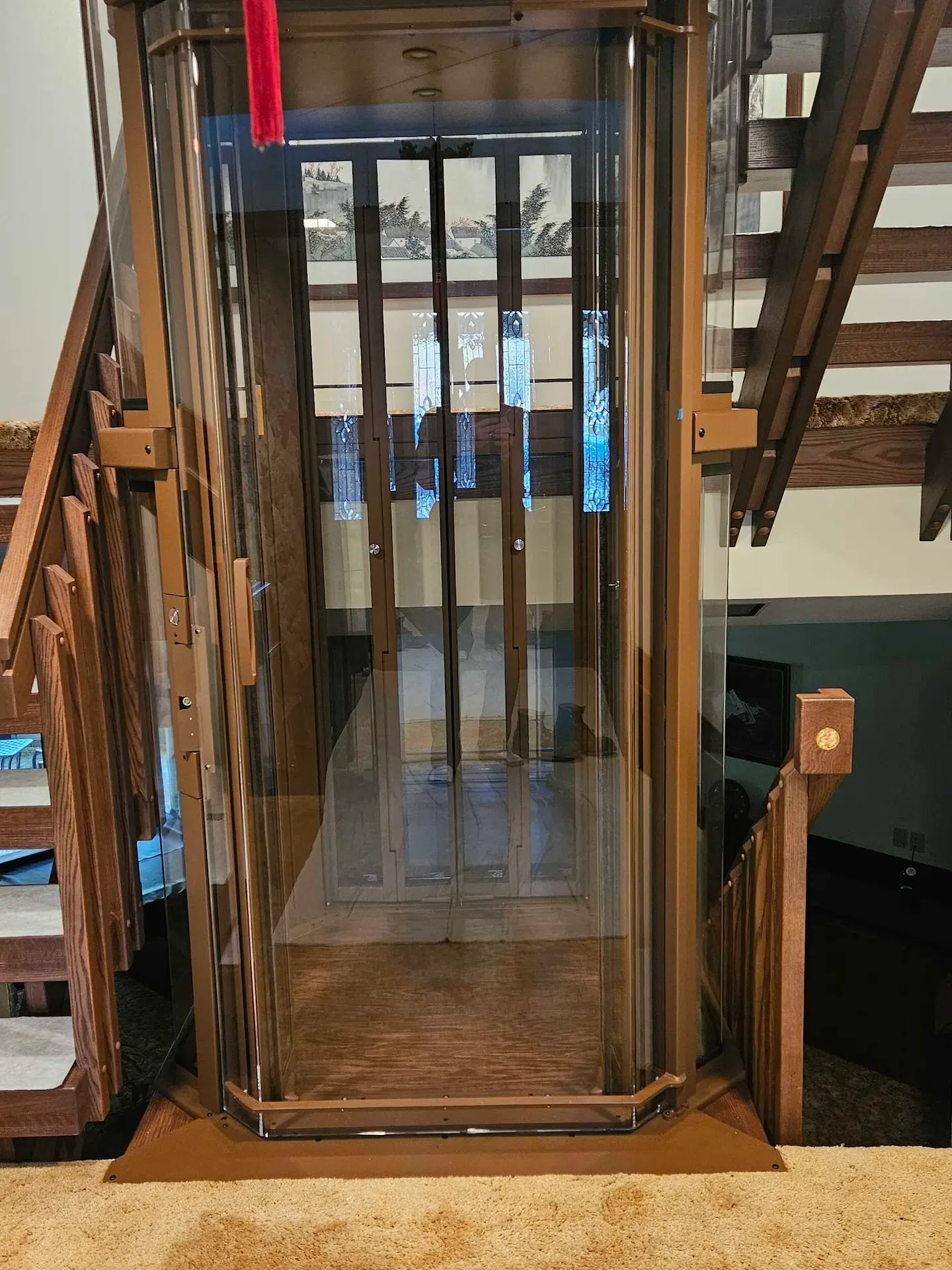 Detail photo of wood railing post and glass elevator structure in a custom residential elevator installation