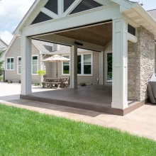 Covered outdoor living area next to the pool with stone fireplace, patio space, and white columns