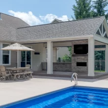 Expanded backyard patio with covered seating area, pool, and outdoor fireplace feature