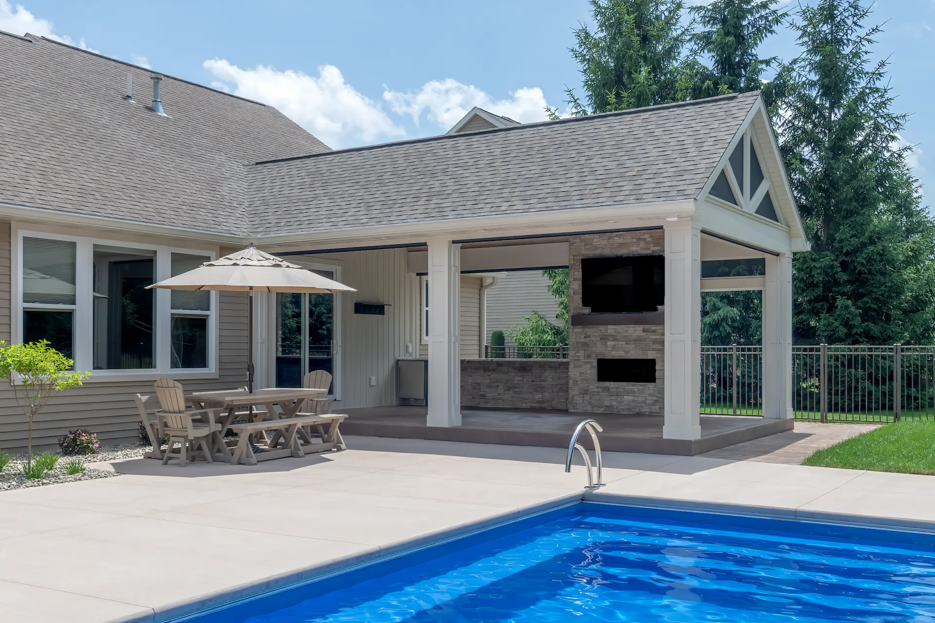 Expanded backyard patio with covered seating area, pool, and outdoor fireplace feature