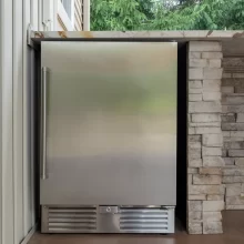 Stainless outdoor refrigerator built into the covered patio next to a stone counter wall