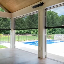 Interior view of the covered patio showing retractable screens and a pool view beyond