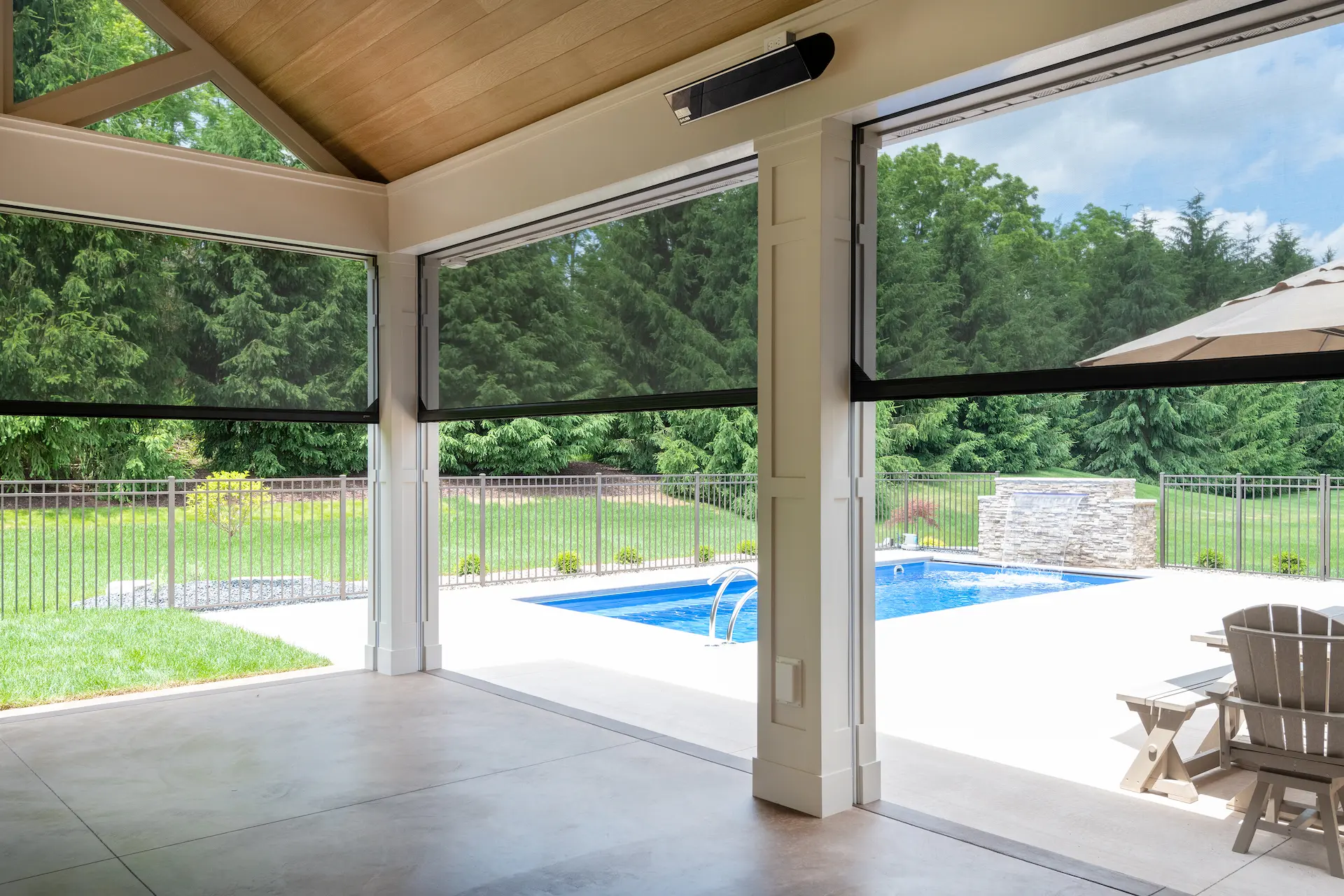 Interior view of the covered patio showing retractable screens and a pool view beyond