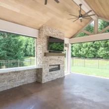 Stone fireplace wall with mounted TV inside a covered backyard patio