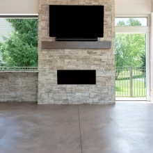 Stone fireplace feature wall with mounted TV and linear fireplace in the covered patio