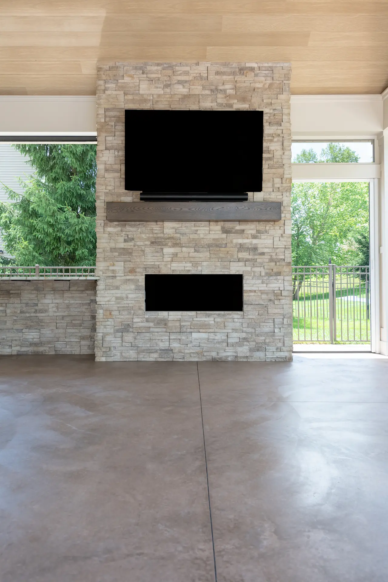 Stone fireplace feature wall with mounted TV and linear fireplace in the covered patio