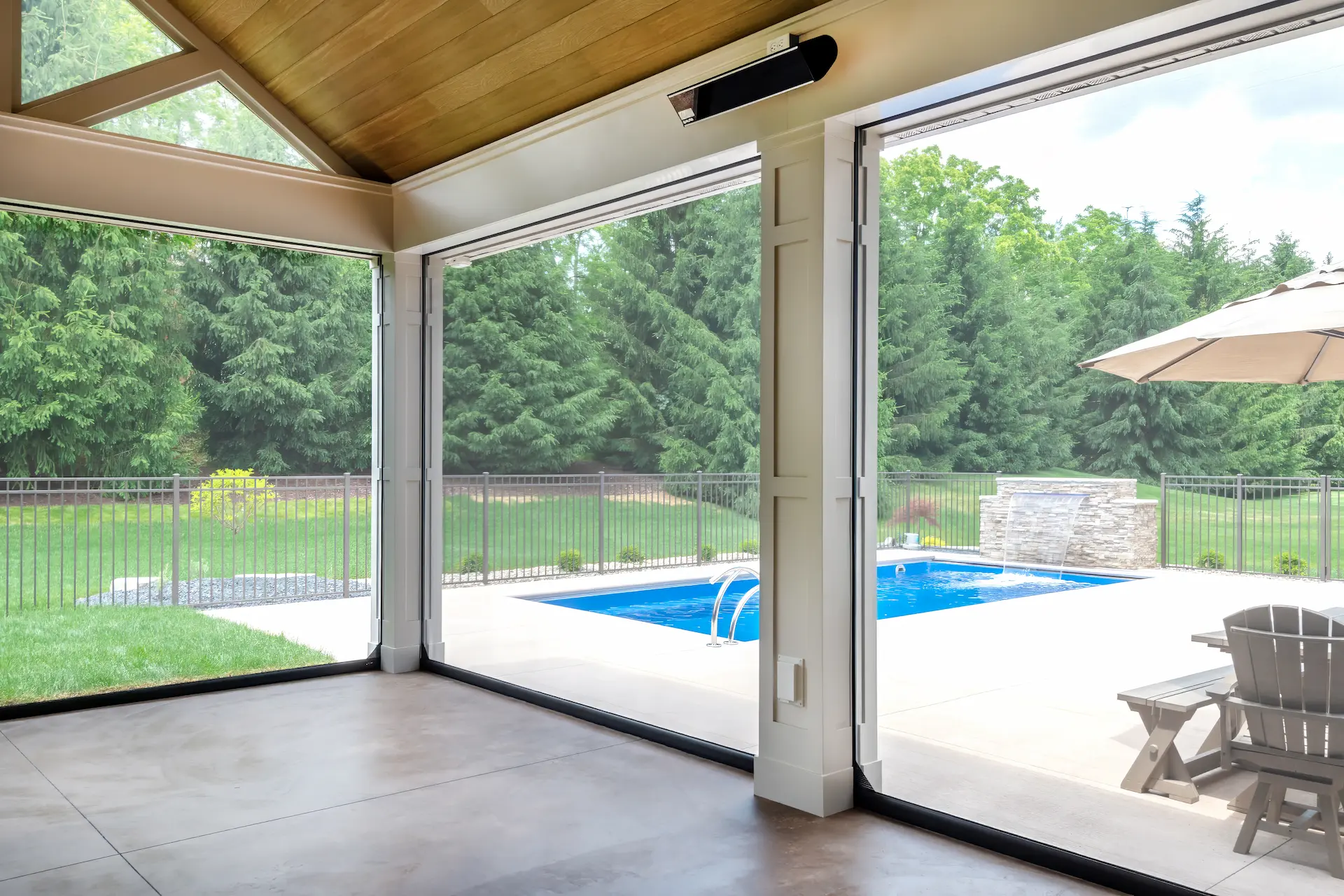 View from inside the covered patio through retractable screens toward the pool and backyard.