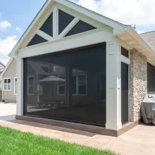 Stone fireplace and TV wall inside the covered patio with retractable screens around the space.